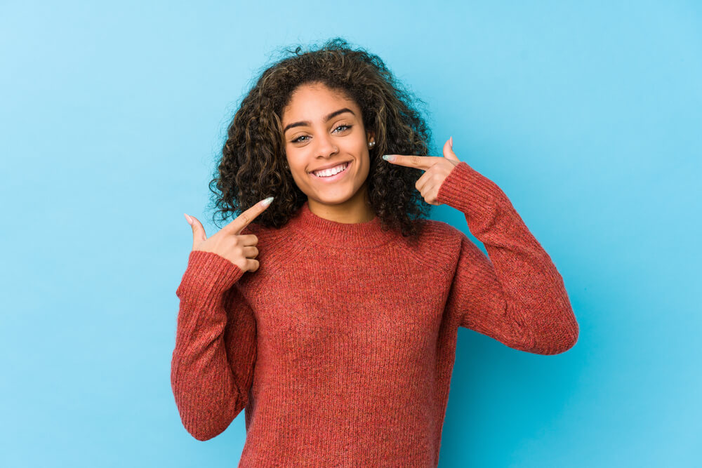 Woman pointing to her smile