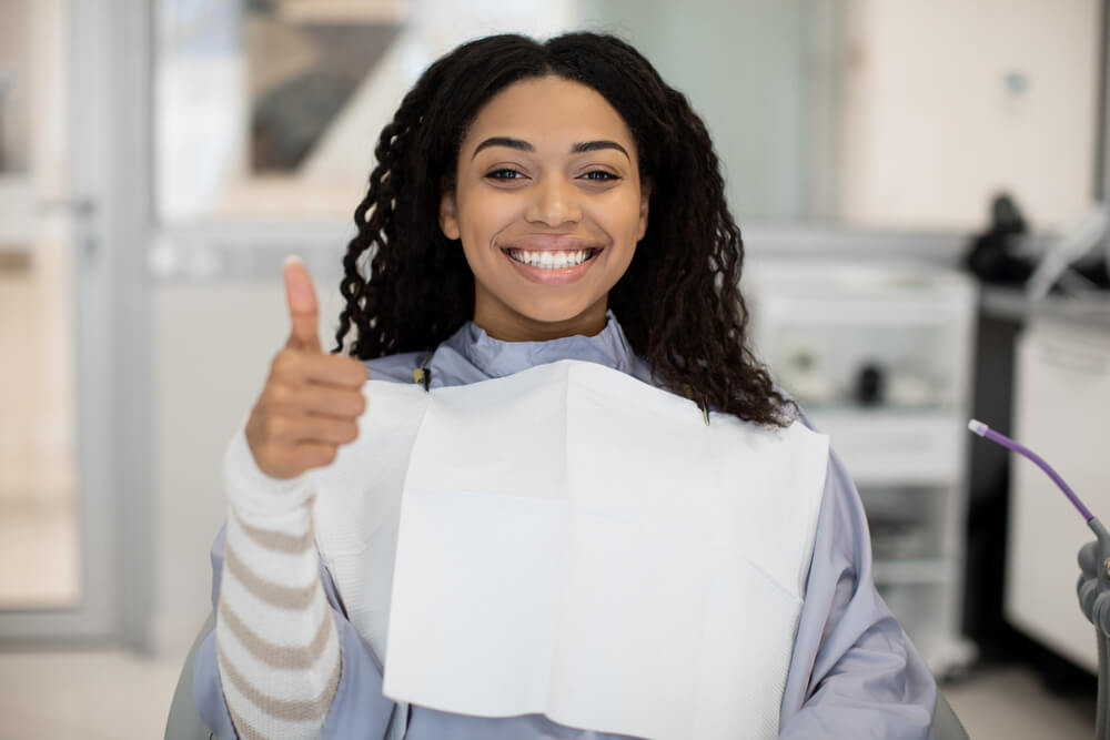 Woman sitting in the dental chair and giving a thumbs up