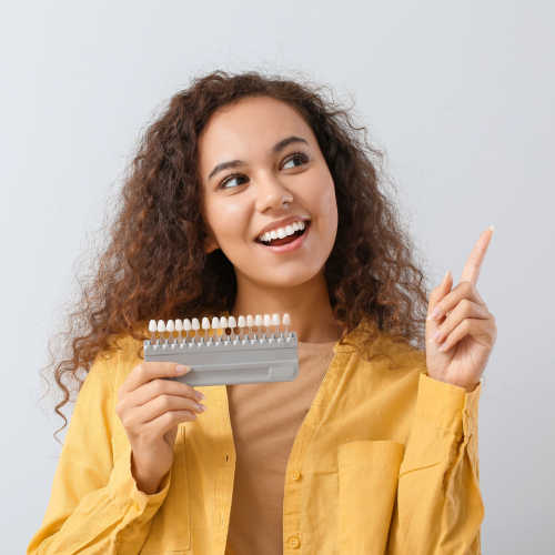 Woman showing different shades of porcelain veneers